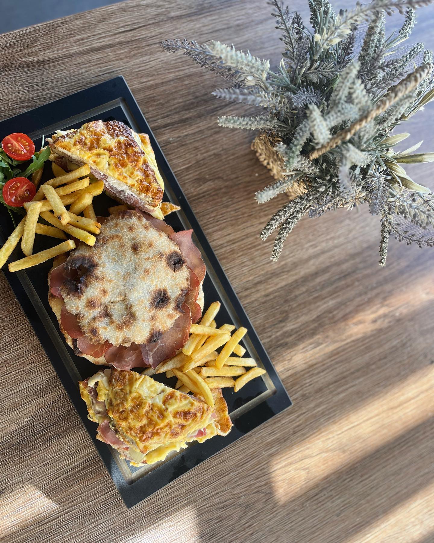 A delicious breakfast plate with a prosciutto sandwich, eggs, and fries.